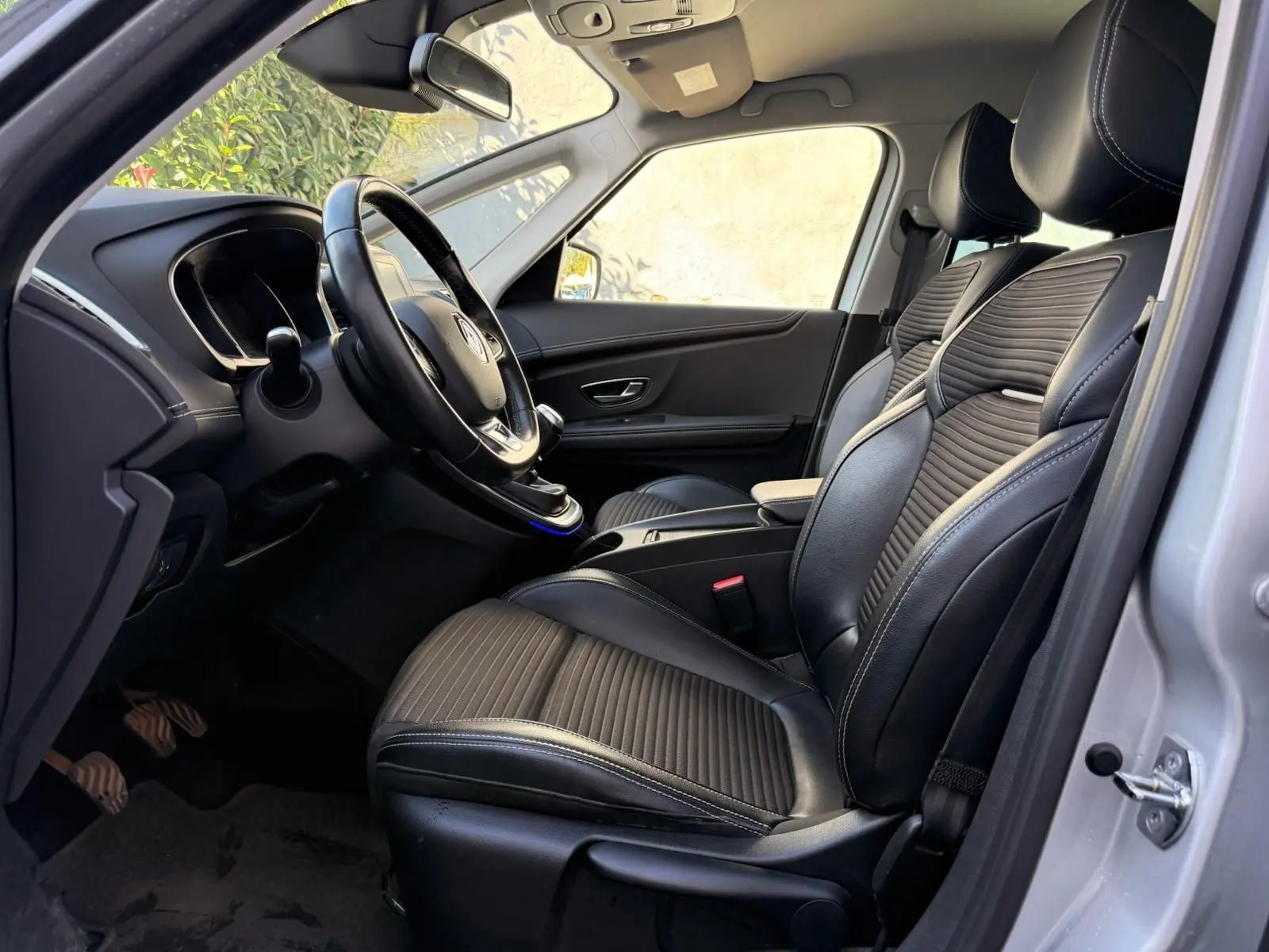 Vue intérieure côté conducteur du Renault Scénic IV 2020, sièges noirs en cuir avec surpiqûres et tableau de bord épuré.