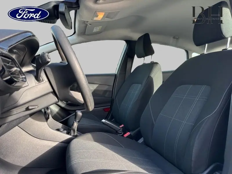 Vue intérieure avant de la Ford Fiesta 2020, sièges tissu noir à motifs, volant et levier de vitesse visibles.
