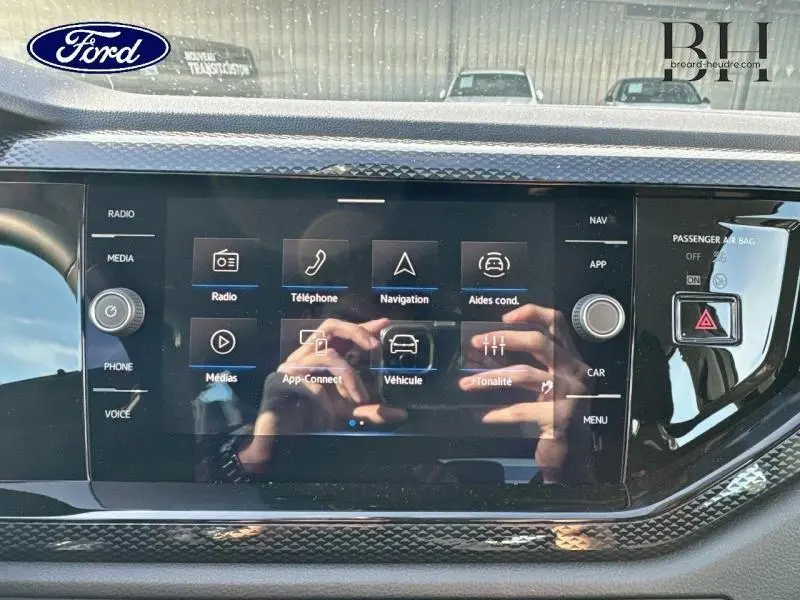 Écran tactile central du tableau de bord d’un Volkswagen Taigo blanc, affichant le menu multimédia et navigation.