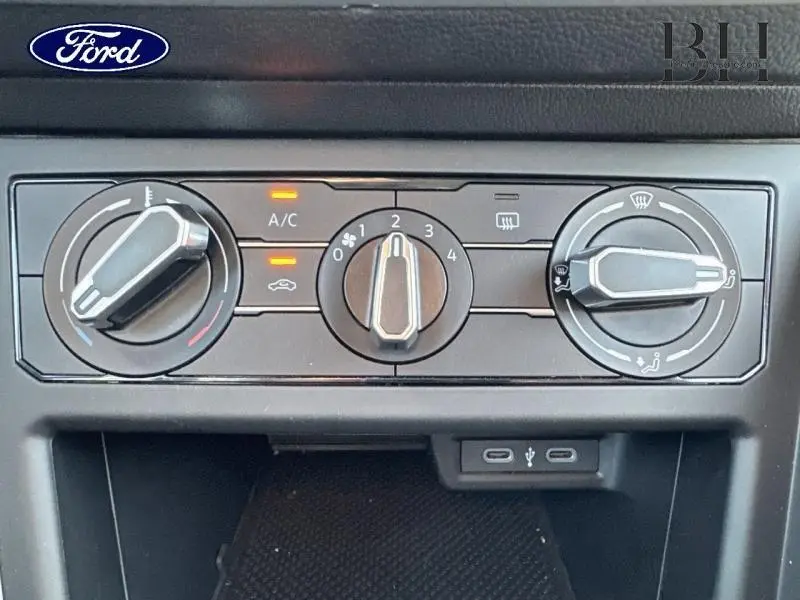 Panneau de commandes de climatisation noir avec trois molettes et deux ports USB, intérieur d’un Volkswagen Taigo blanc.