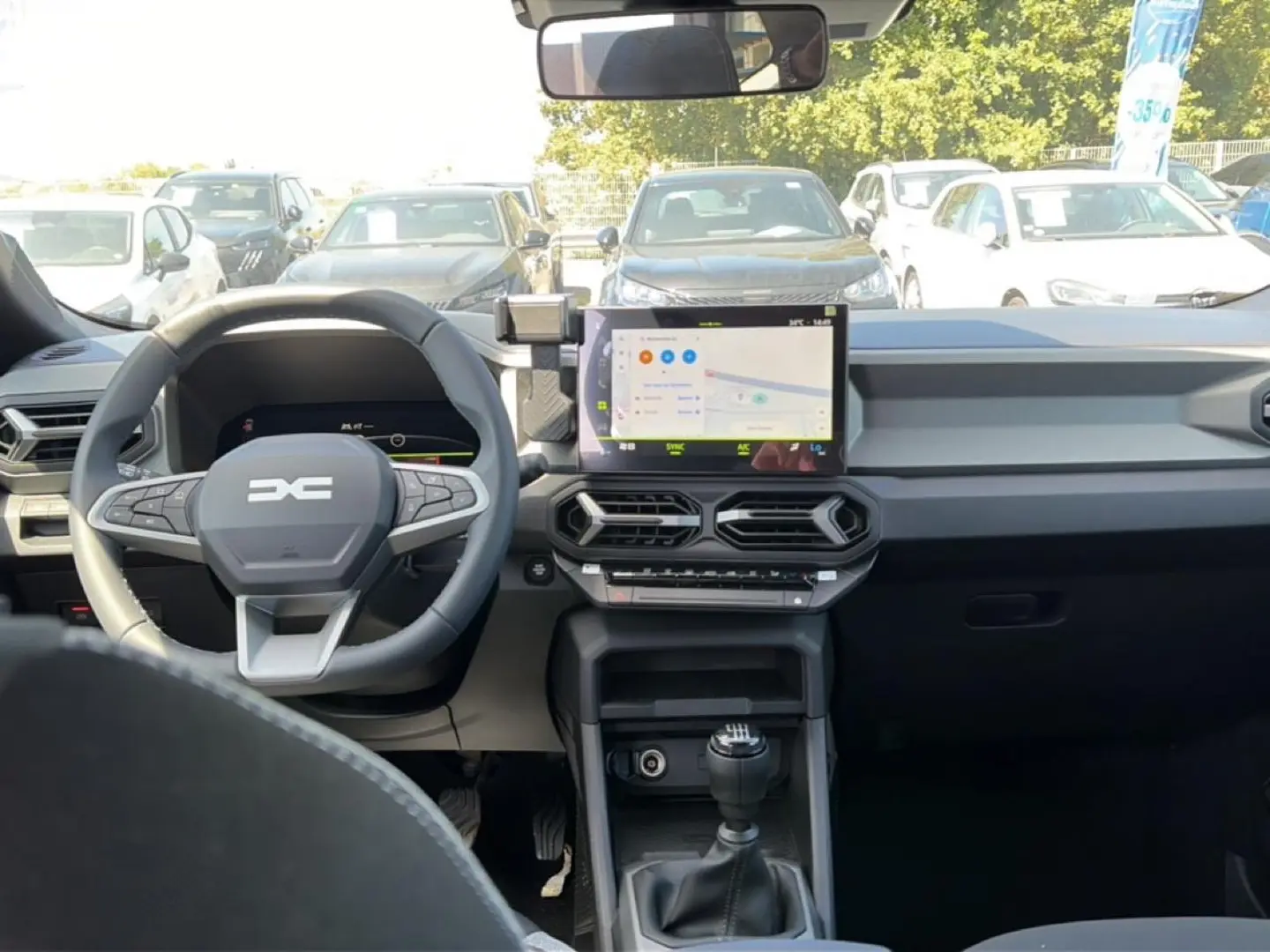 Vue intérieure avant du tableau de bord et volant gris du Dacia Bigster 2026 avec écran tactile et levier de vitesse manuel.