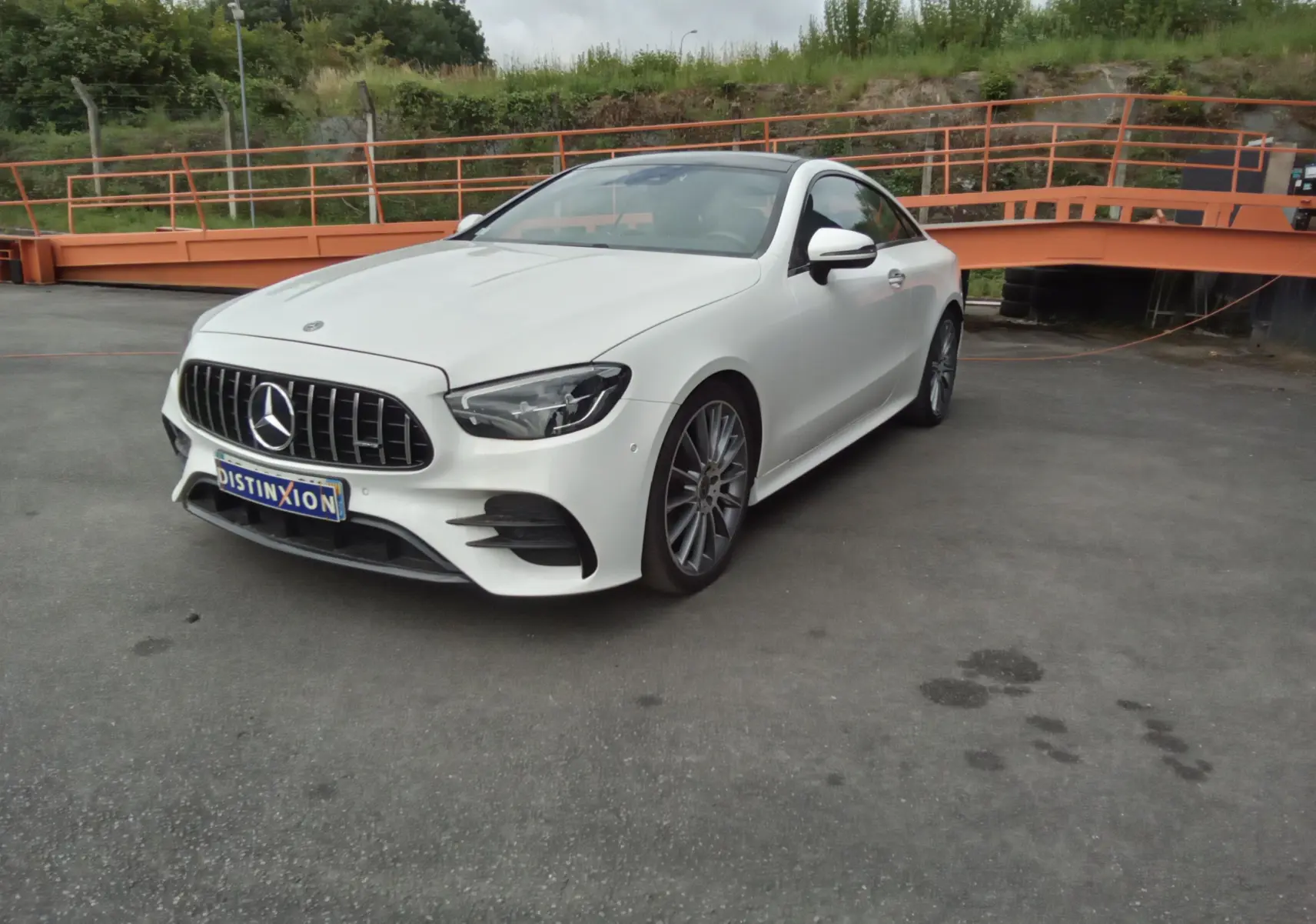 Mercedes Classe E Coupé 220D AMG Line blanc vue 3/4 avant avec calandre AMG et jantes alliage 19 pouces