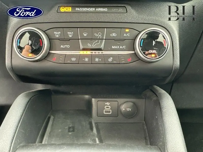 Vue rapprochée de la console centrale du Ford Kuga 2022 avec commandes climatisation et prises USB et 12V visibles.