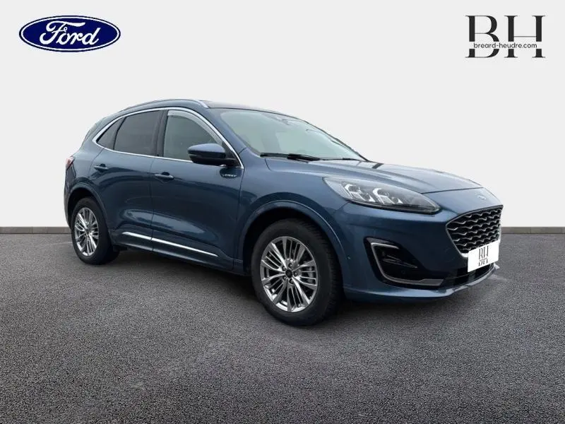 Ford Kuga bleu azur métallisé en 3/4 avant droit avec toit panoramique et jantes alu visibles.