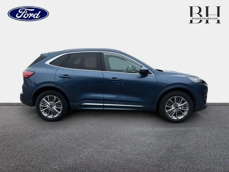 Ford Kuga bleu azur métallisé vu de profil côté gauche avec toit panoramique et jantes alu.