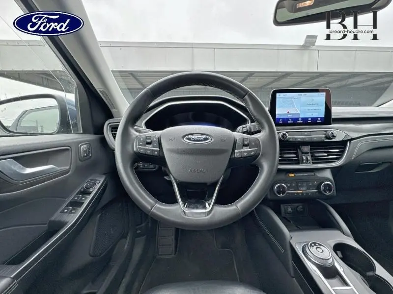 Vue intérieure centrée sur le volant cuir multifonction noir du Ford Kuga 2022 avec écran tactile et commandes au tableau de bord.
