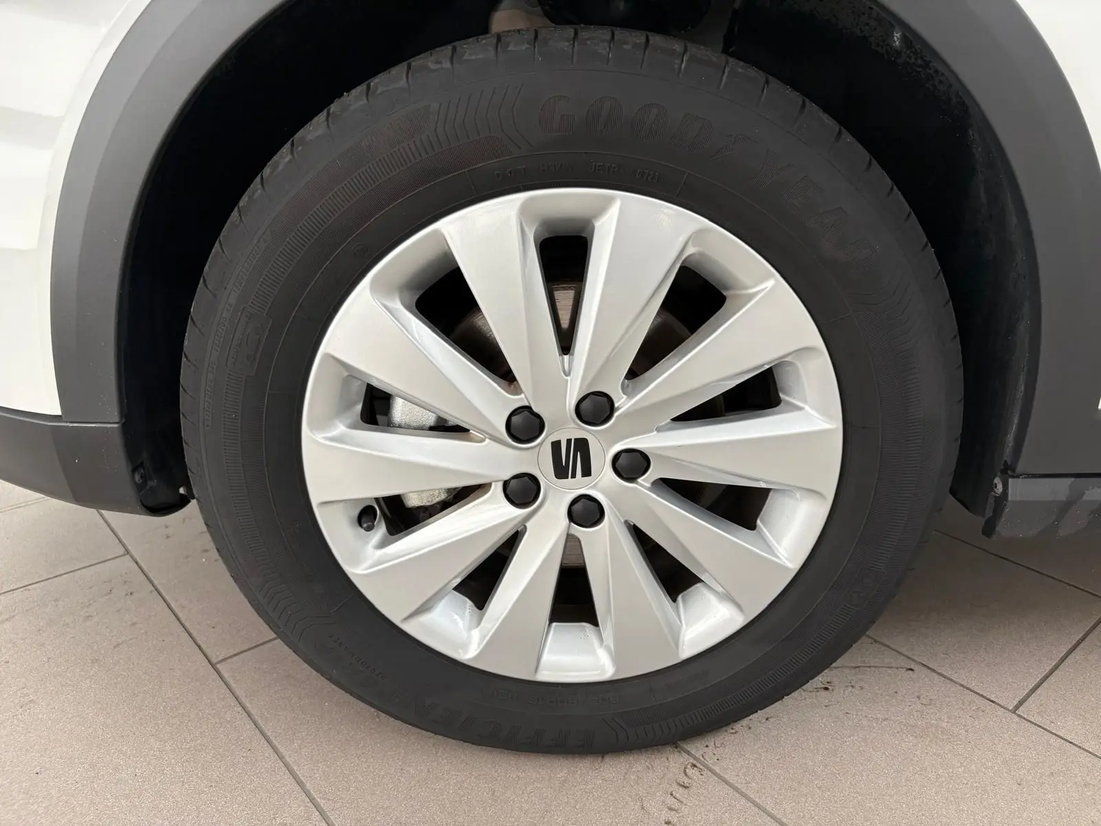 Gros plan sur la roue avant gauche du SEAT Arona blanc toit noir, avec jante en alliage argentée et logo central noir.