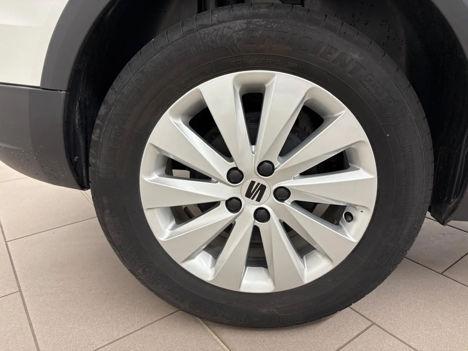 Gros plan sur la roue avant droite d'une SEAT Arona 2023 blanc toit noir avec jante argentée à dix branches.