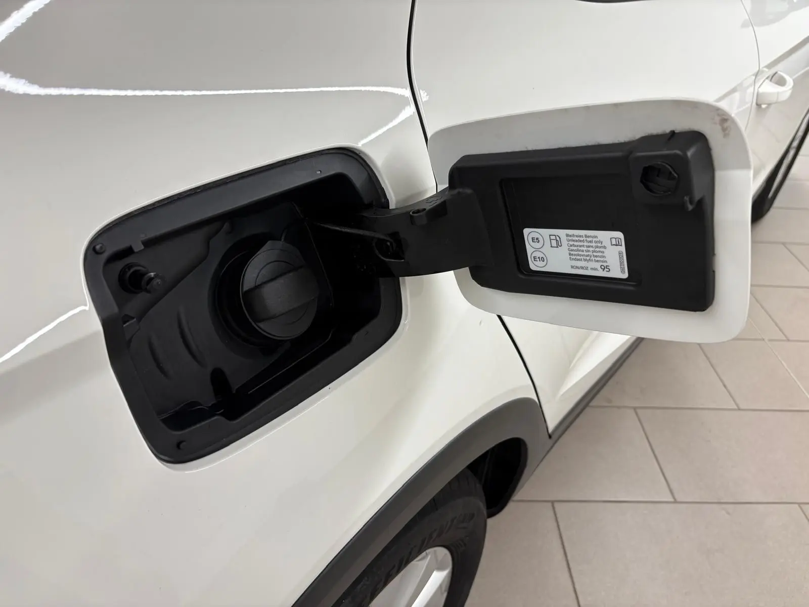 Vue rapprochée du bouchon de carburant ouvert côté gauche d'un SEAT Arona blanc avec toit noir.