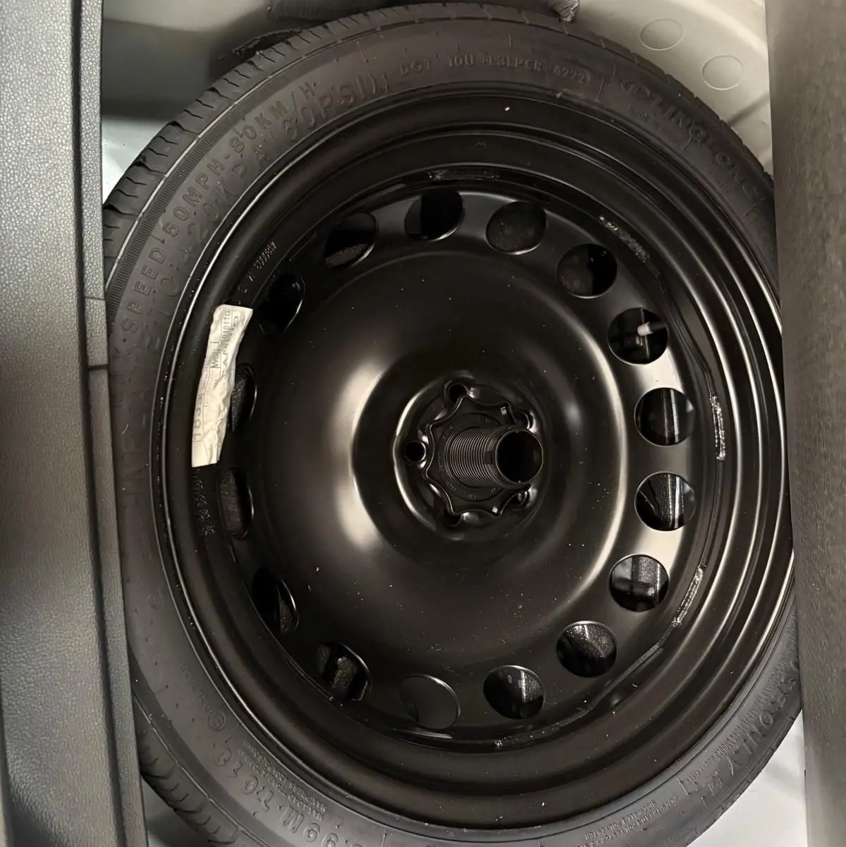 Gros plan sur la roue de secours noire dans le coffre d'un SEAT Arona blanc toit noir 2023.