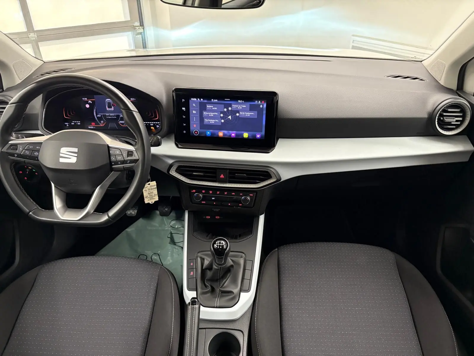 Intérieur avant du SEAT Arona 2023, tableau de bord moderne avec écran tactile et levier de vitesse manuel visible.