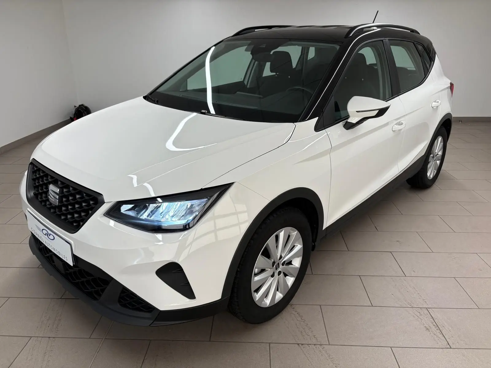 SEAT Arona blanc avec toit noir vu en 3/4 avant droit, mettant en valeur ses phares LED et sa calandre noire.