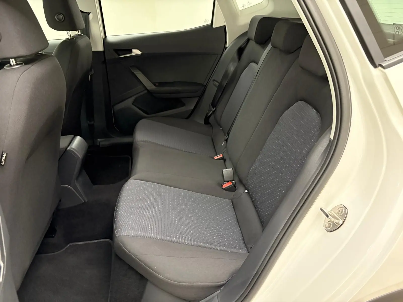 Vue intérieure côté droit des sièges arrière noirs du SEAT Arona 2023 avec portière blanche ouverte.