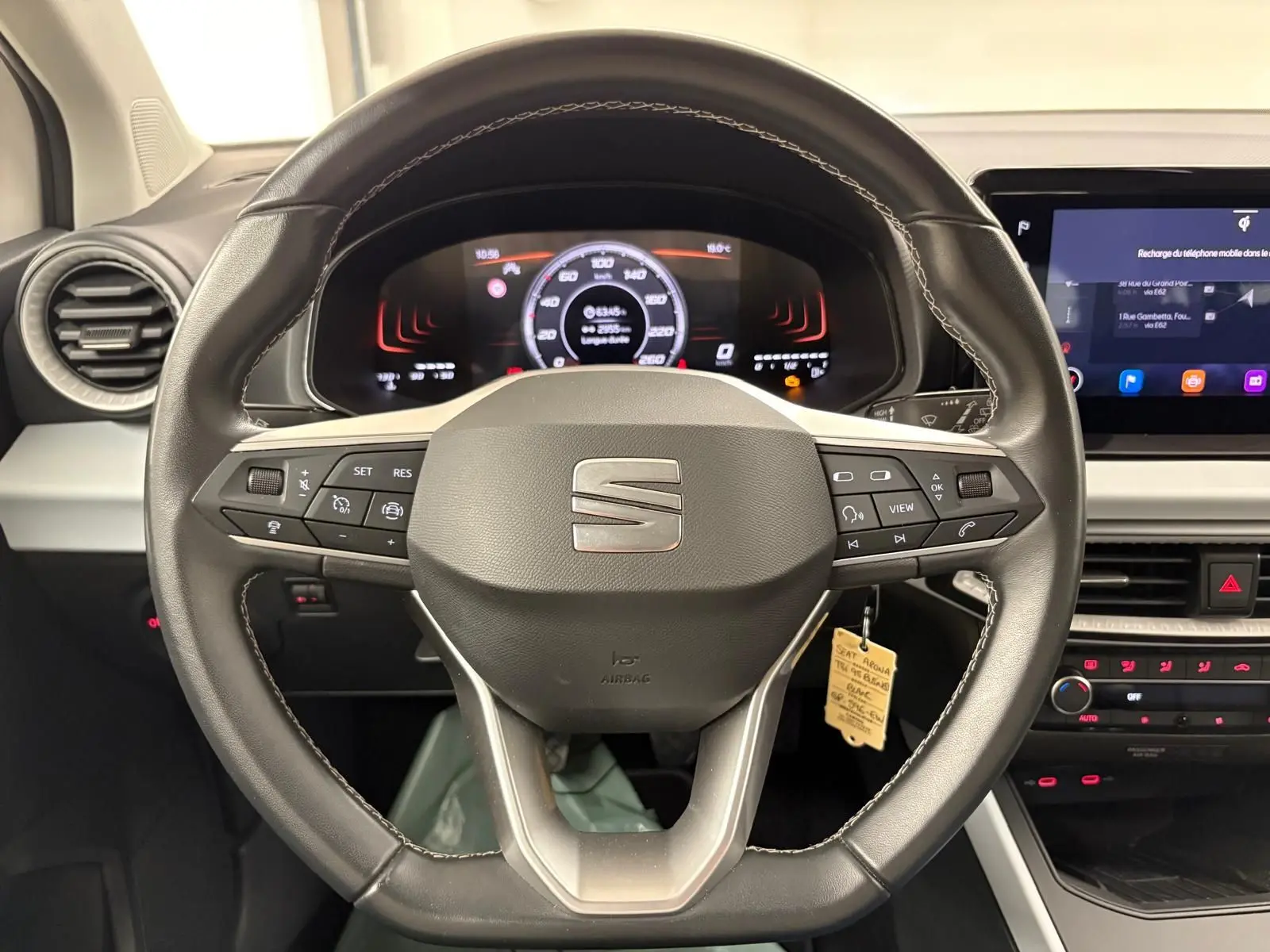 Vue rapprochée du volant en cuir noir du SEAT Arona 2023 avec tableau de bord numérique et écran tactile central.