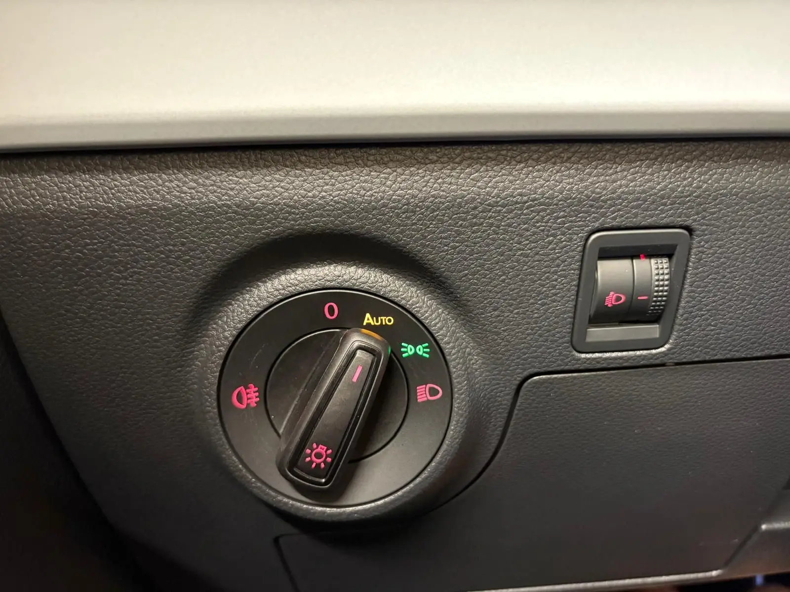 Gros plan sur la molette de réglage des phares du tableau de bord noir d'une SEAT ARONA 2023.