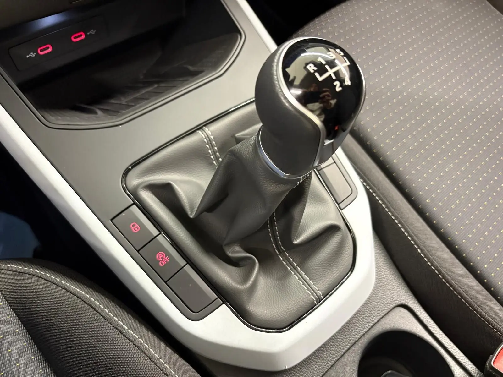 Gros plan sur le levier de vitesses manuel et la console centrale du SEAT Arona 2023 avec sellerie noire à surpiqûres blanches.