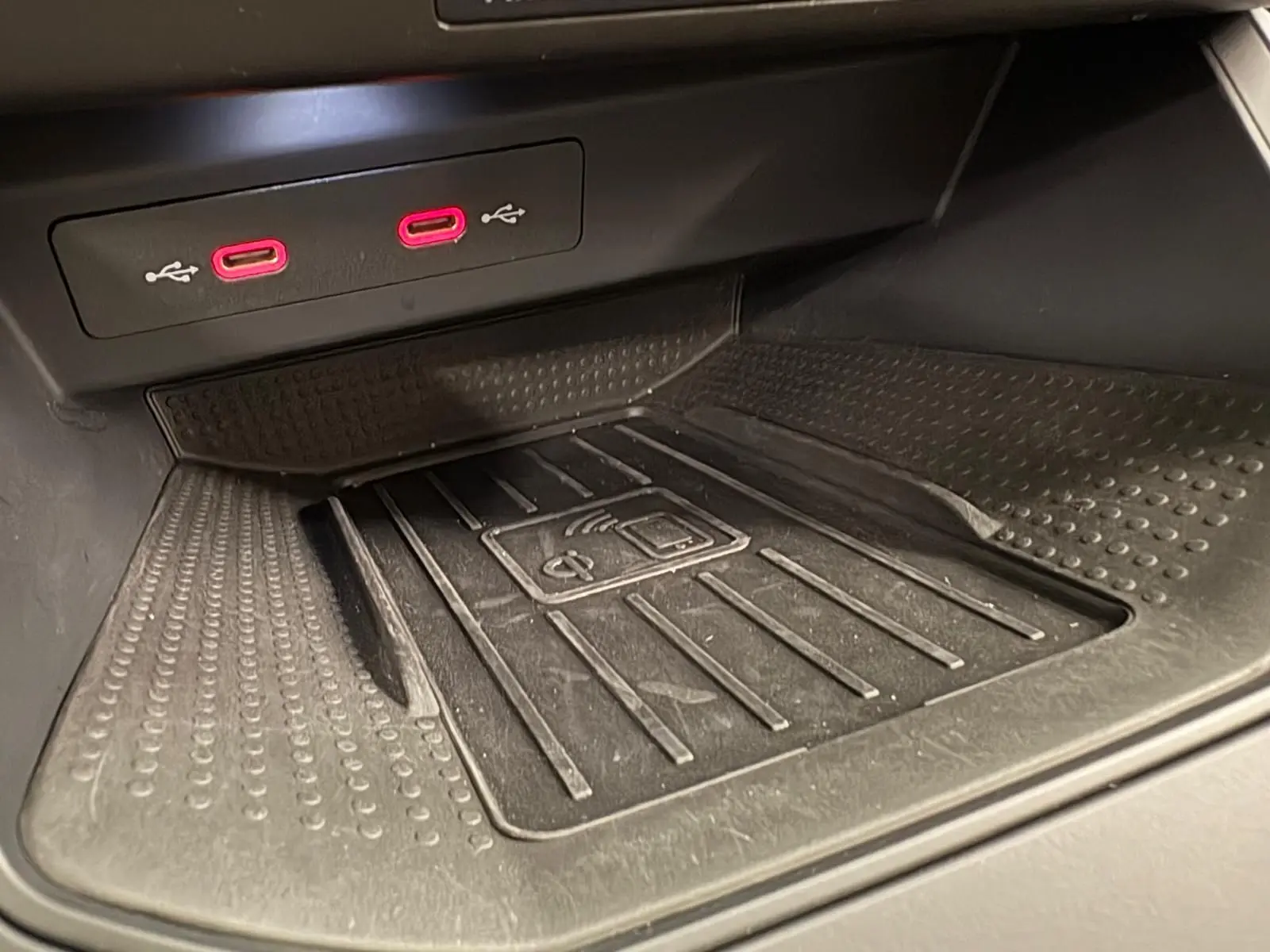 Gros plan sur la zone de recharge sans fil et les deux ports USB rouges dans l'habitacle du SEAT Arona 2023.