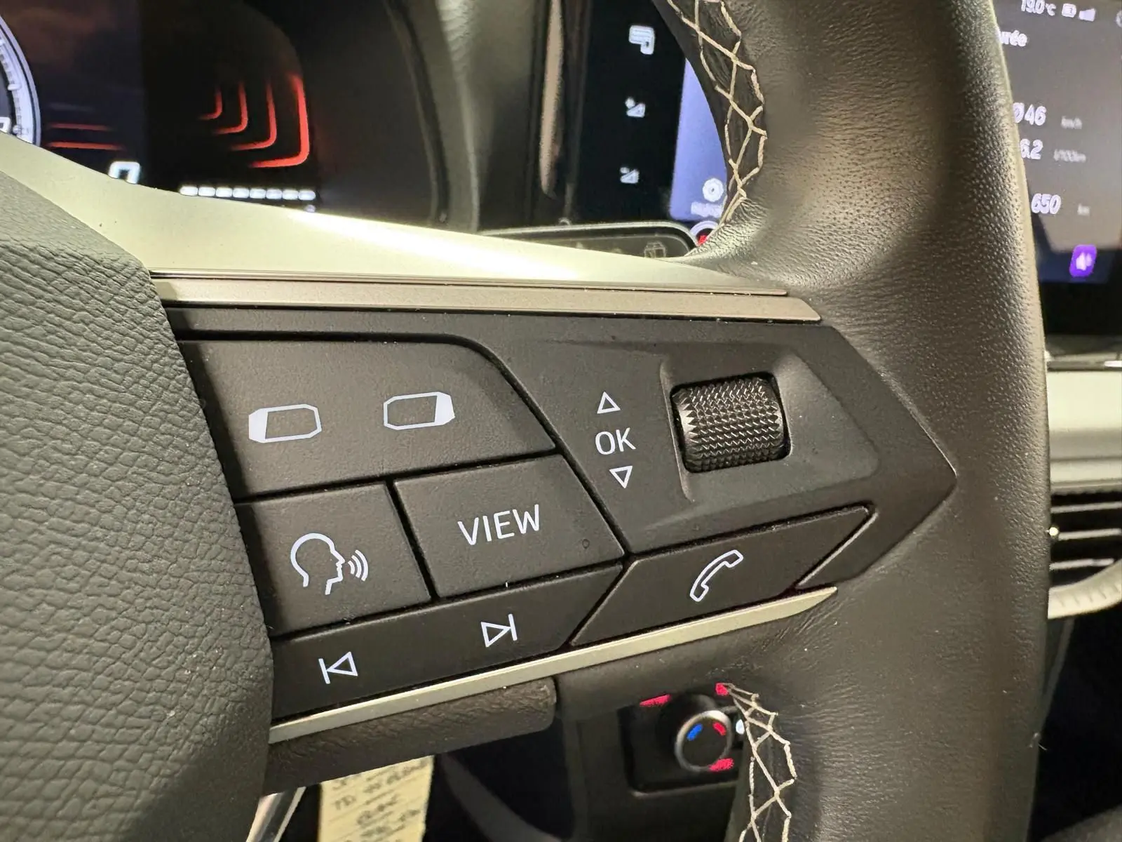 Gros plan sur les commandes au volant en cuir noir avec surpiqûres blanches du SEAT Arona blanc toit noir 2023.