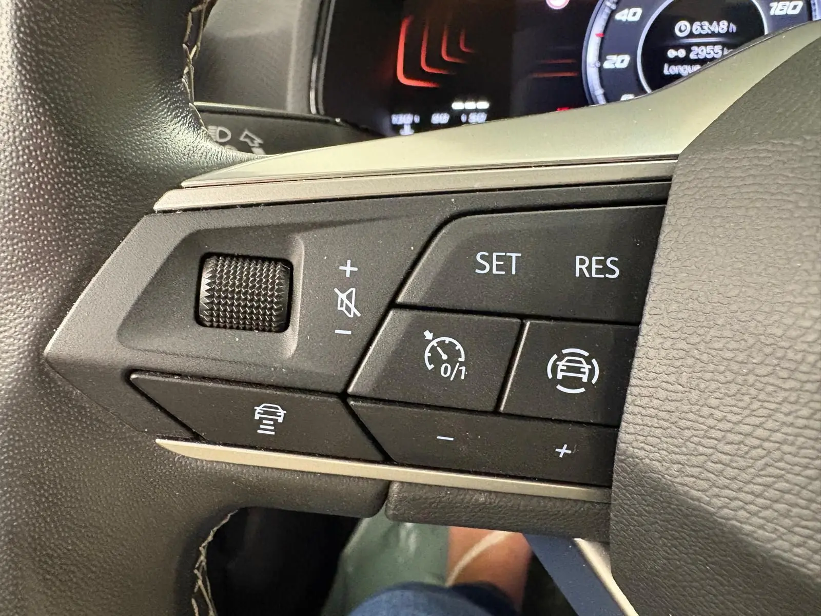 Gros plan sur les commandes de régulateur de vitesse au volant du SEAT ARONA 2023 blanc toit noir.