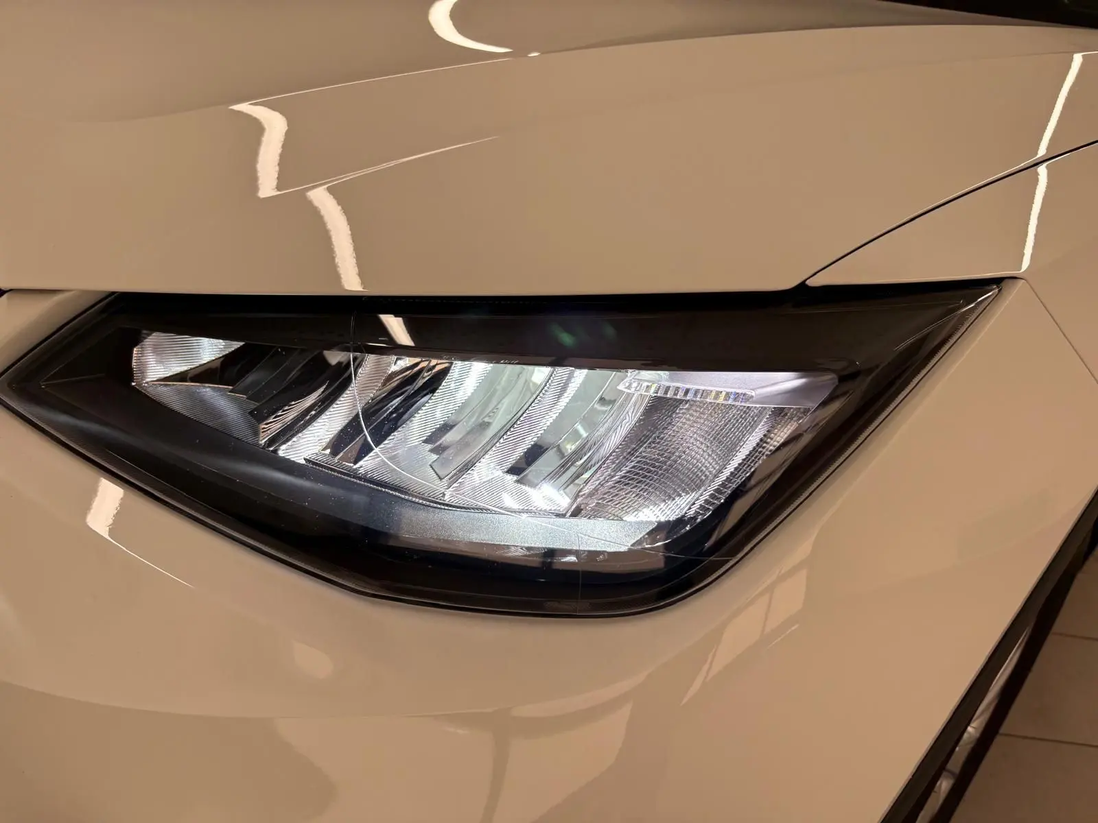 Gros plan sur le phare avant droit du SEAT Arona blanc avec toit noir, soulignant le design moderne et épuré.