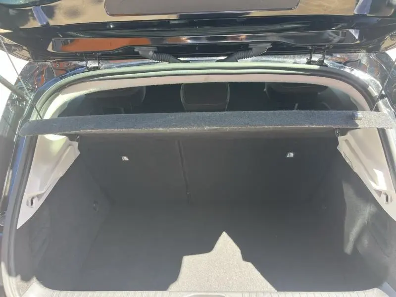 Coffre ouvert vu de l'arrière d'une Renault Clio noir étoile, montrant la tablette cache-bagages et l'intérieur vide.