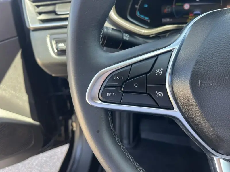 Gros plan sur les commandes du régulateur de vitesse au volant noir de la Renault Clio 1.6 E-Tech 2020.