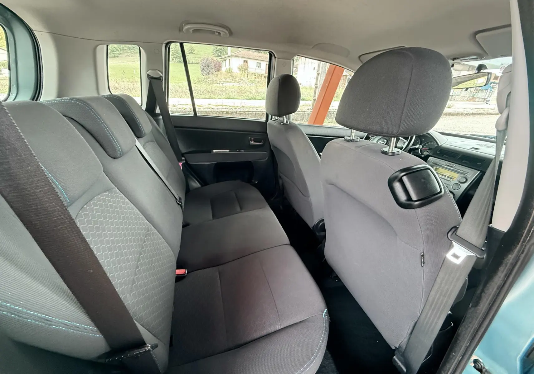 Vue intérieure côté gauche montrant les sièges arrière en tissu noir de la Mazda2 gris 5 portes de 2004.