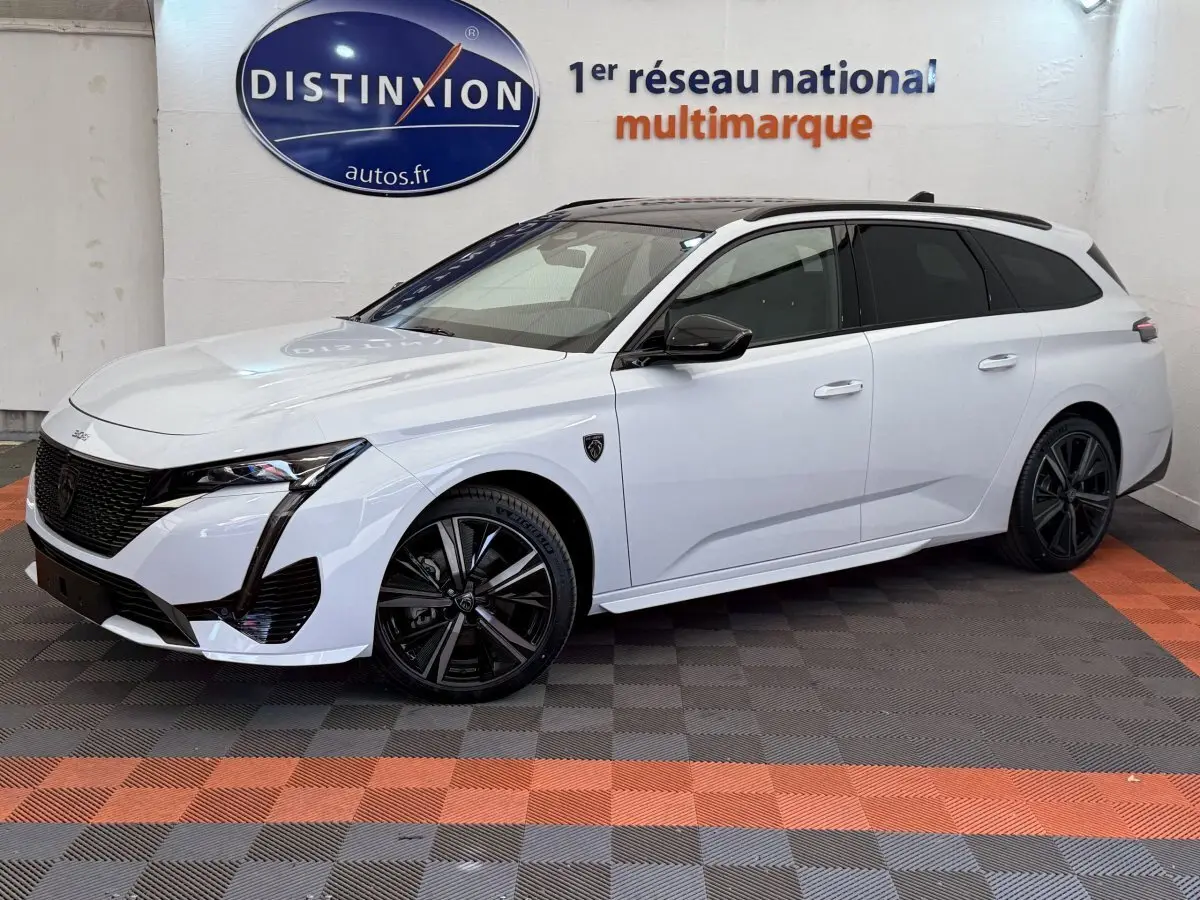 Peugeot 308 Hybrid 136 e-DCS6 GT blanche vue de 3/4 avant droit avec jantes noires et toit noir.