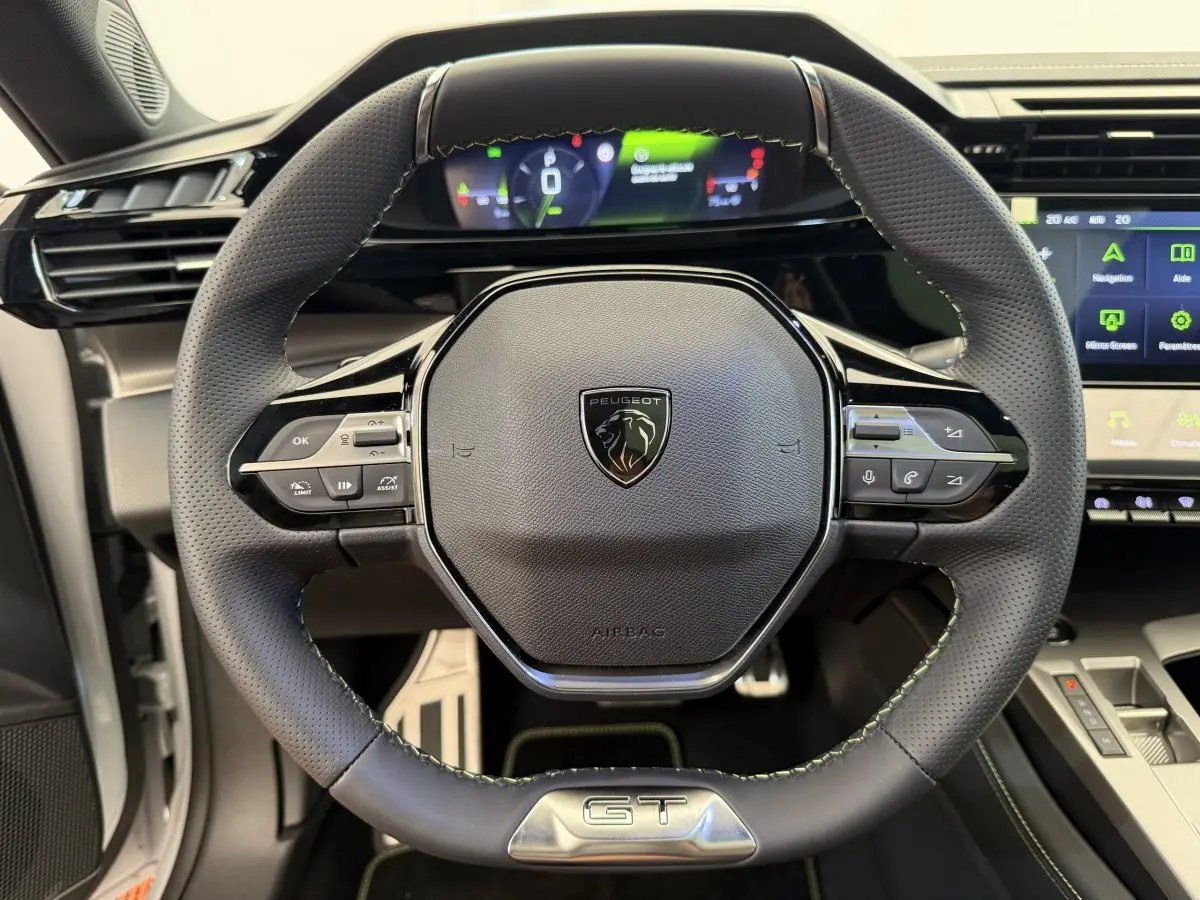 Volant cuir noir avec logo Peugeot et badge GT, tableau de bord numérique et écran tactile de la Peugeot 308 Hybrid 2024.