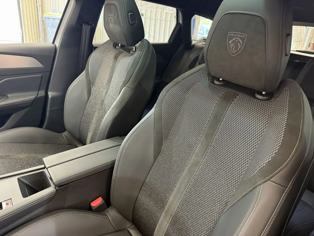 Gros plan sur les sièges avant noirs en cuir et tissu de la Peugeot 308 Hybrid 136 e-DCS6 GT 2024.