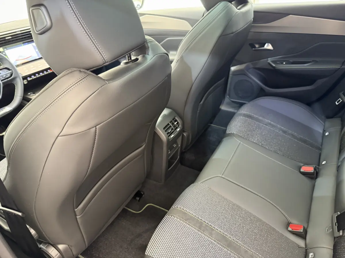Vue intérieure arrière côté droit du Peugeot 308 Hybrid 136 e-DCS6 GT 2024 avec sièges noirs en cuir et tissu.