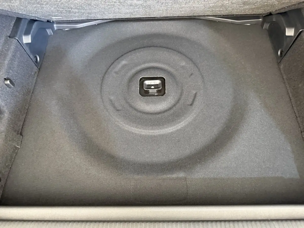 Coffre de Peugeot 308 Hybrid 136 e-DCS6 GT 2024, vue plongeante sur le rangement sous plancher gris foncé.