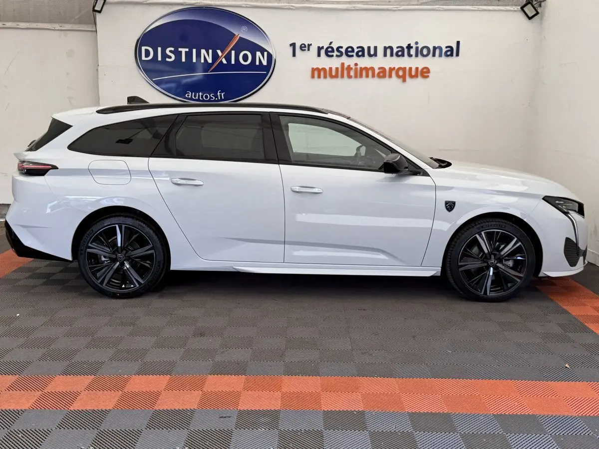 Profil droit d'une Peugeot 308 Hybrid 136 e-DCS6 GT blanche, avec jantes noires et toit ouvrant panoramique.