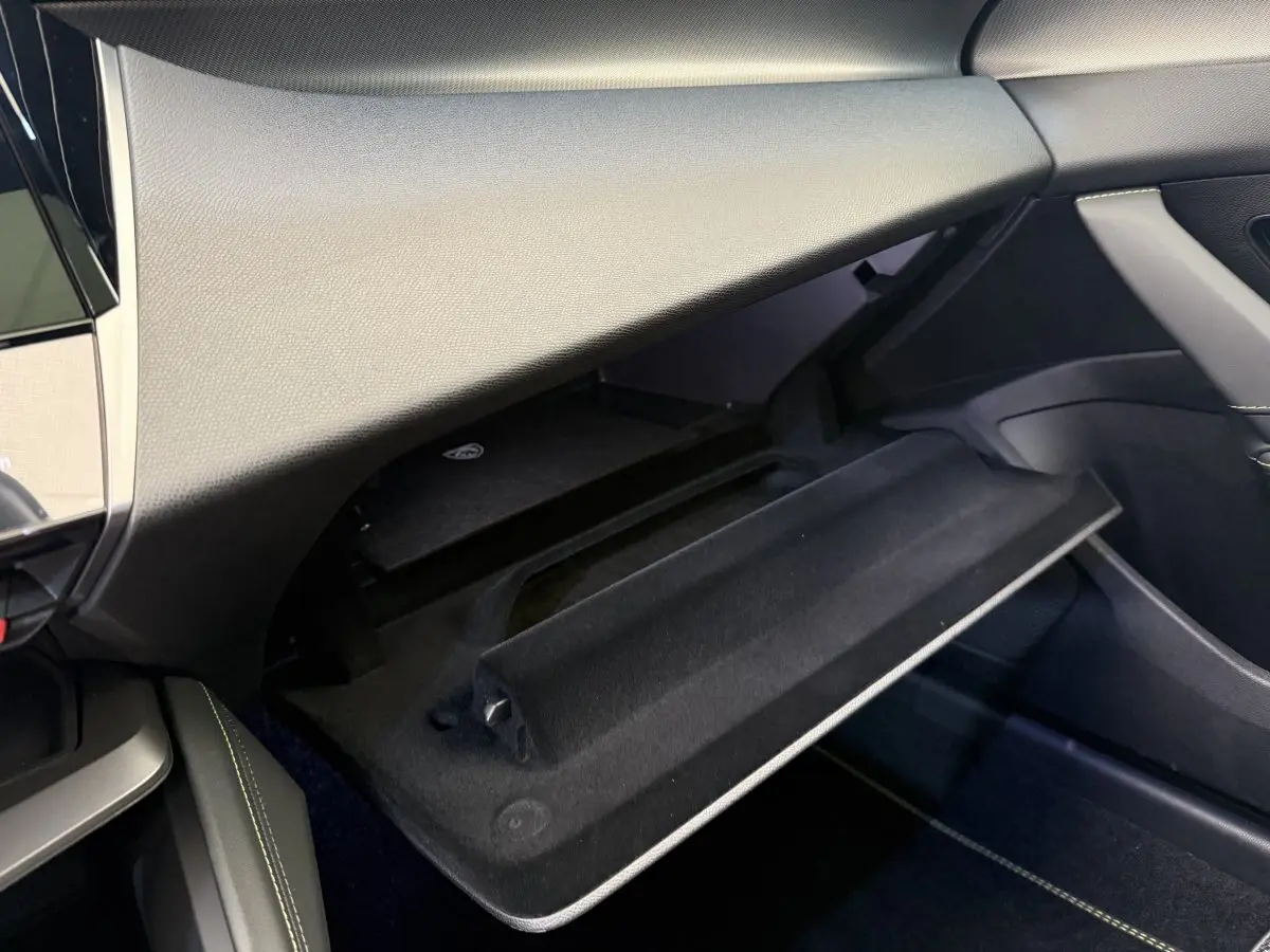 Intérieur Peugeot 308 Hybrid 136 e-DCS6 GT 2024, vue sur boîte à gants ouverte côté passager, finition noire élégante.