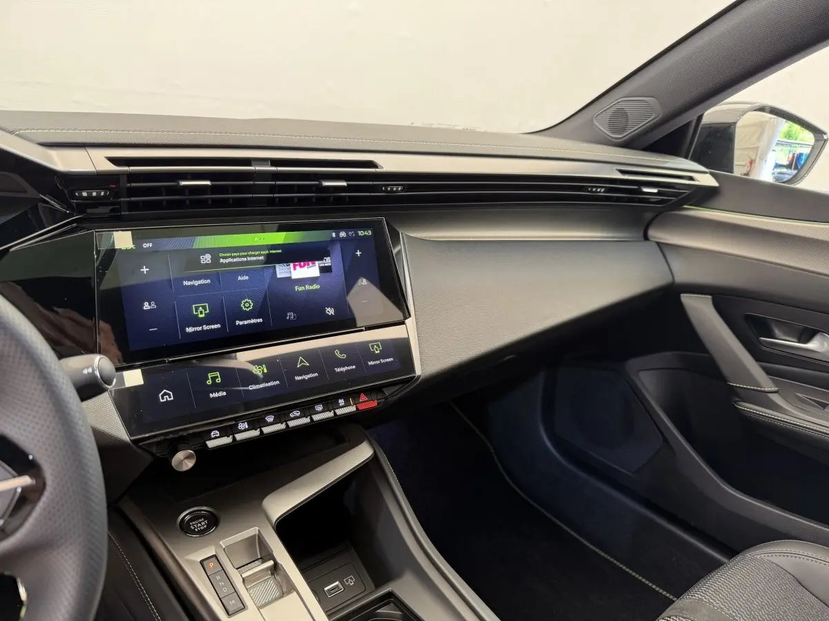 Vue intérieure côté passager du tableau de bord noir et écran tactile 10 pouces de la Peugeot 308 Hybrid 2024 blanche