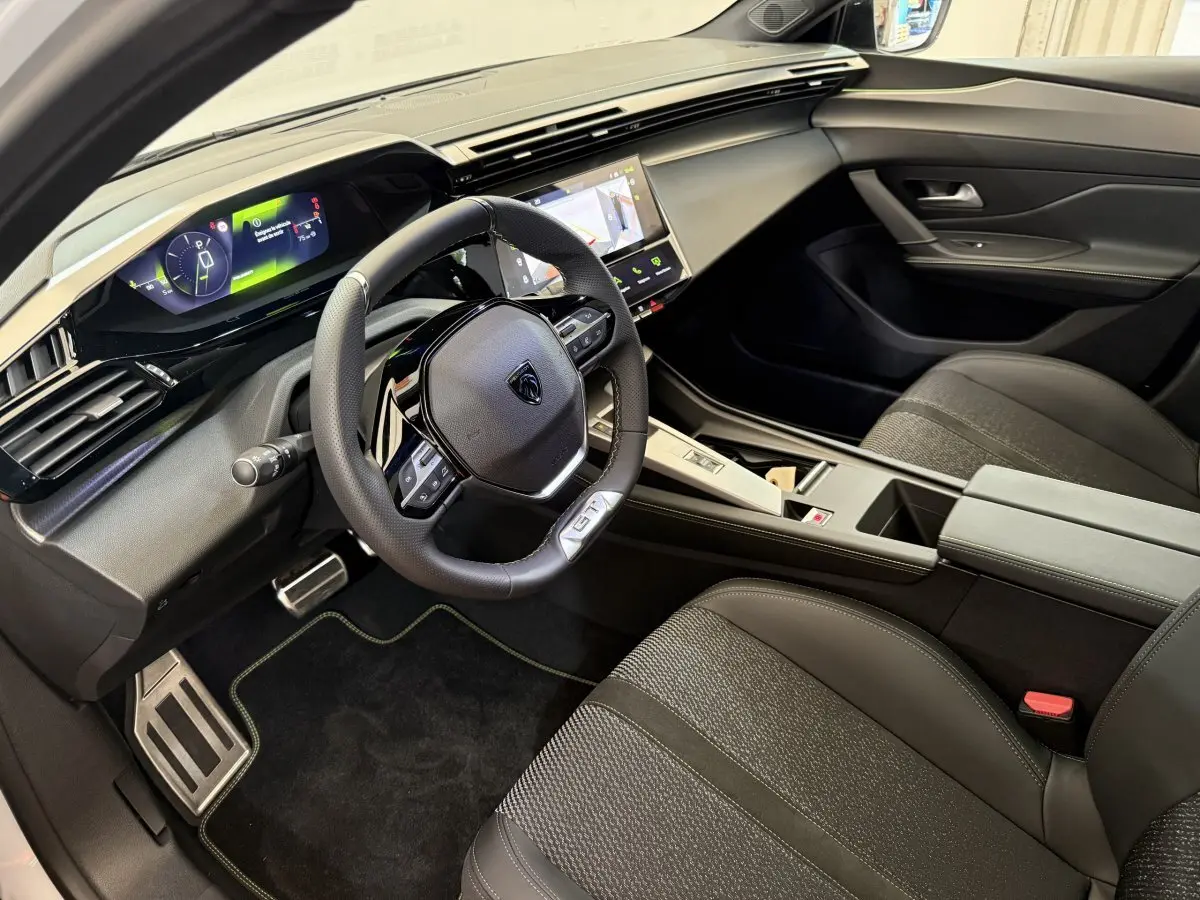 Intérieur noir de la Peugeot 308 Hybrid 136 GT vu côté conducteur, avec tableau de bord digital et volant cuir GT.