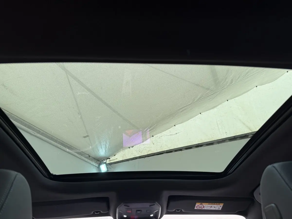 Toit panoramique ouvert vu de l'intérieur arrière d'une Peugeot 308 Hybrid 136 e-DCS6 GT blanche, 2024