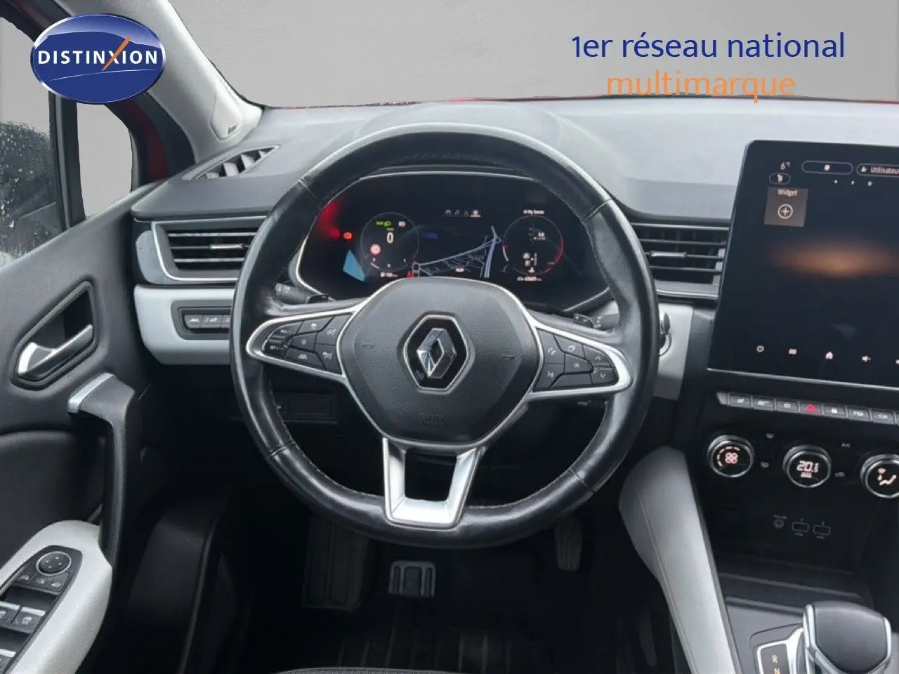 Vue intérieure centrée sur le volant et le tableau de bord numérique du Renault Captur rouge flamme, avec écran tactile.