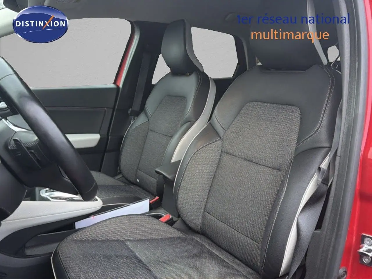 Vue intérieure côté avant droit du Renault Captur rouge flamme, mettant en valeur les sièges bi-matière gris et noir.
