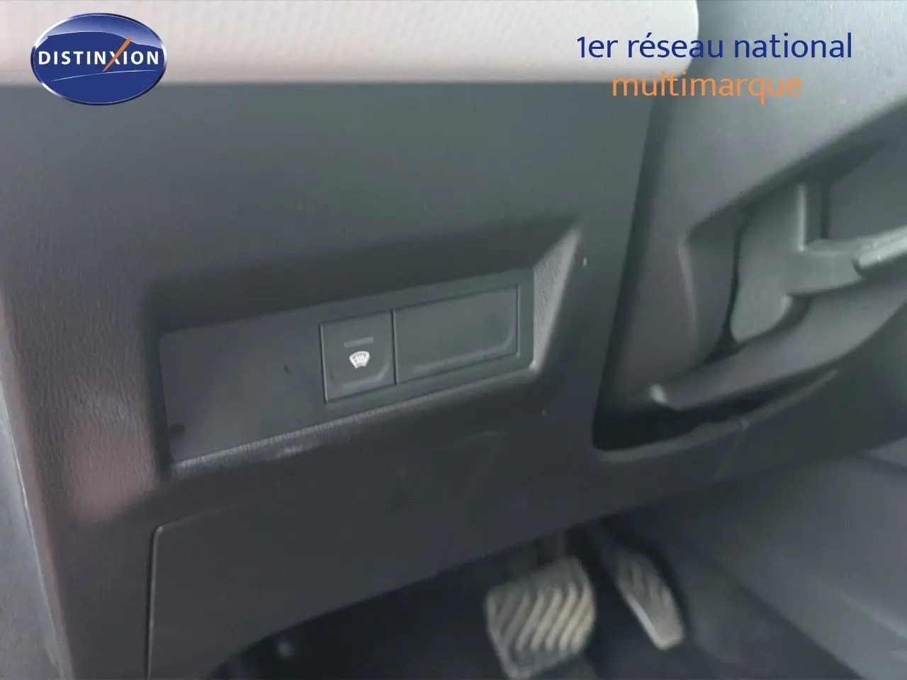 Détail intérieur montrant le bouton de dégivrage et les pédales côté conducteur d’un Renault Captur rouge flamme 2020.