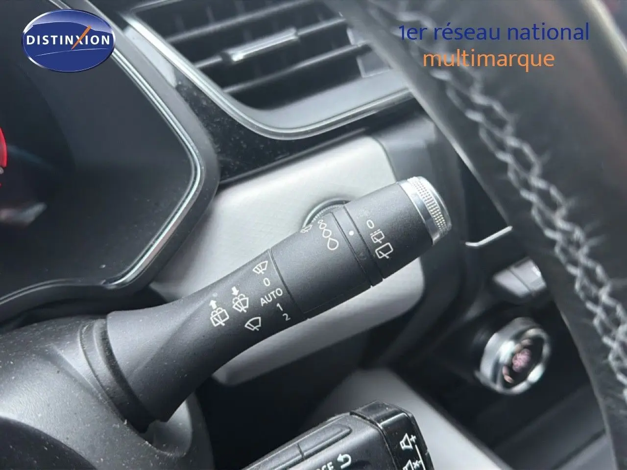 Gros plan sur la commande des essuie-glaces à gauche du volant dans l’habitacle du Renault Captur rouge flamme.