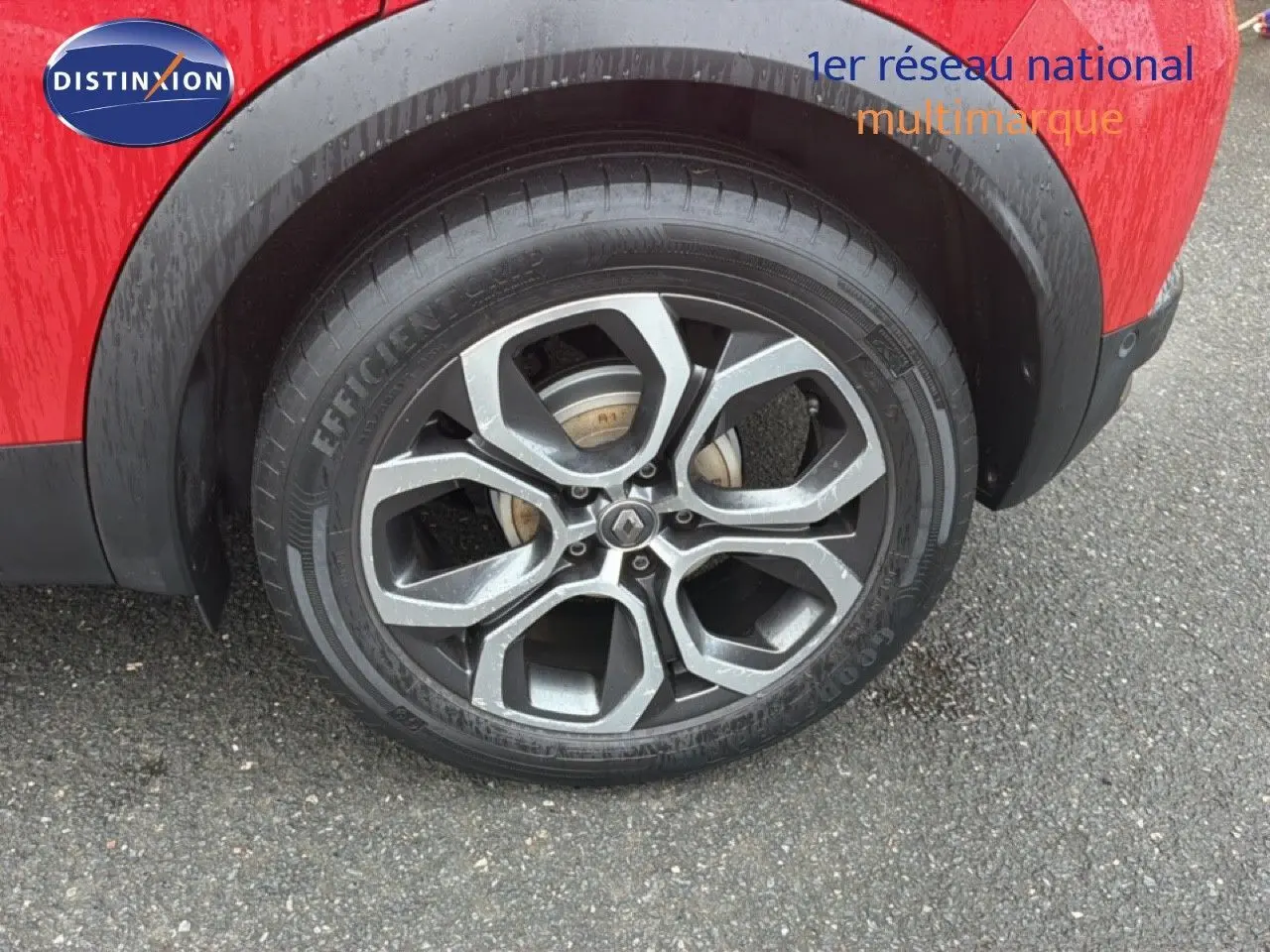 Gros plan sur la roue arrière droite d’un Renault Captur rouge flamme avec jante alliage à motifs géométriques.