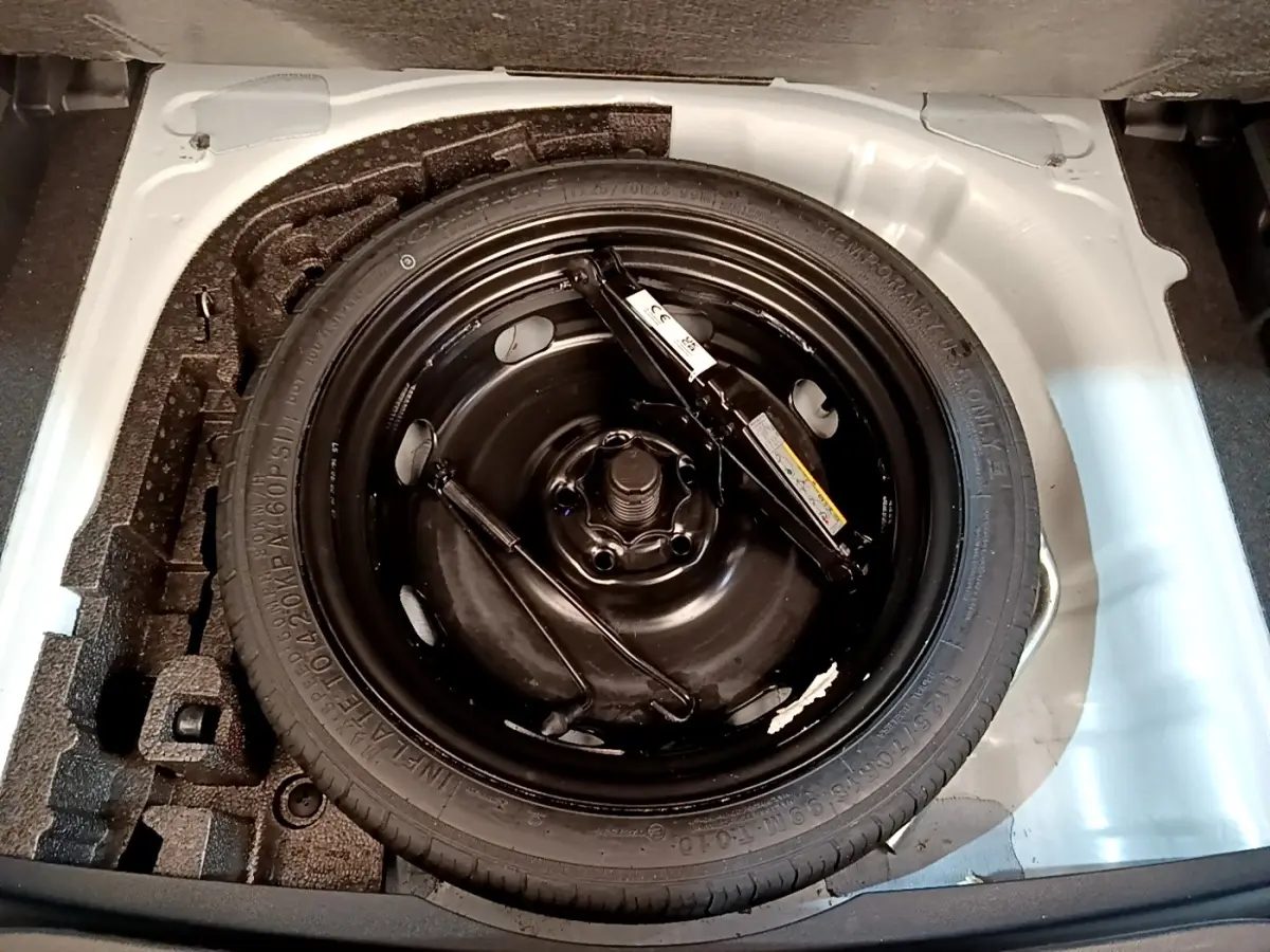 Gros plan sur la roue de secours galette noire dans le coffre blanc d'une CUPRA Formentor 2023.