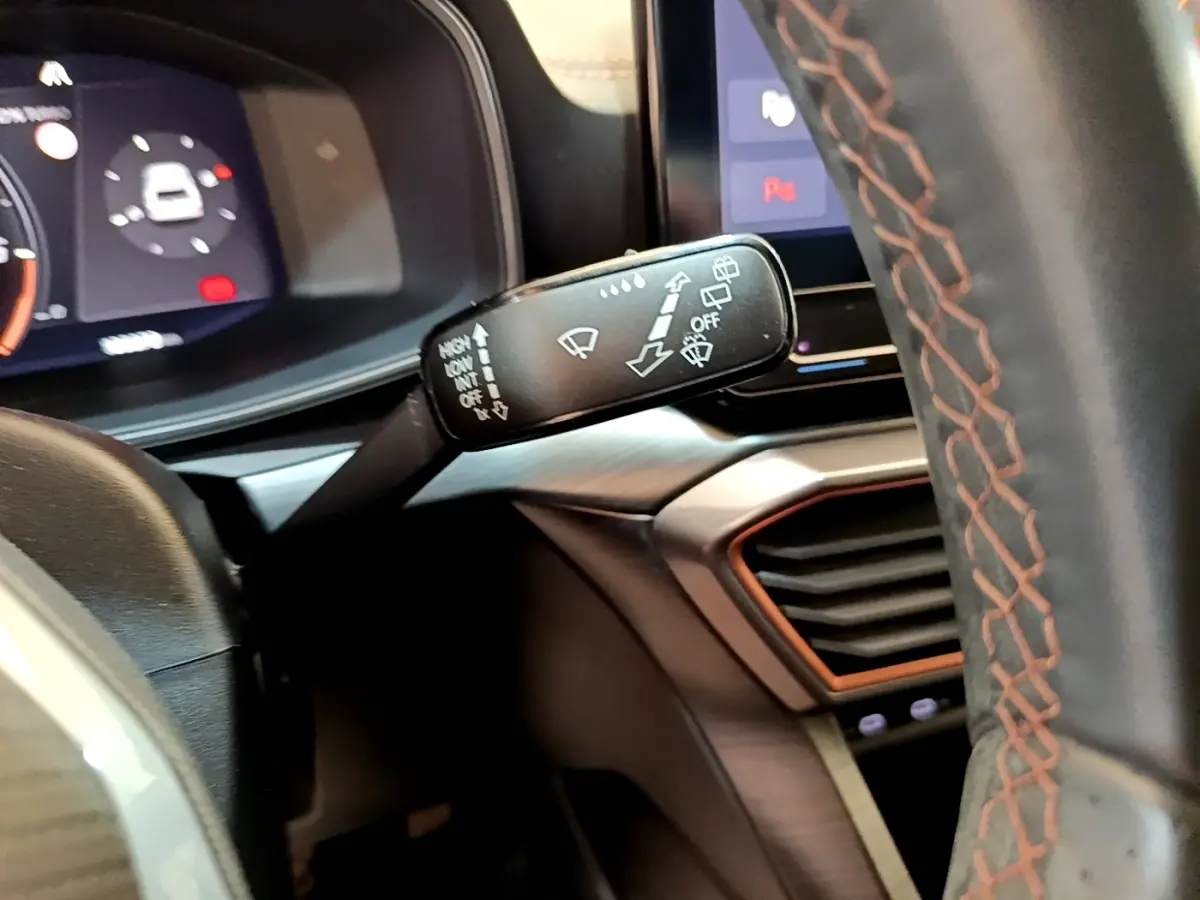 Gros plan sur la manette d’essuie-glace à gauche du volant cuir noir avec surpiqûres orange du CUPRA Formentor 2023.