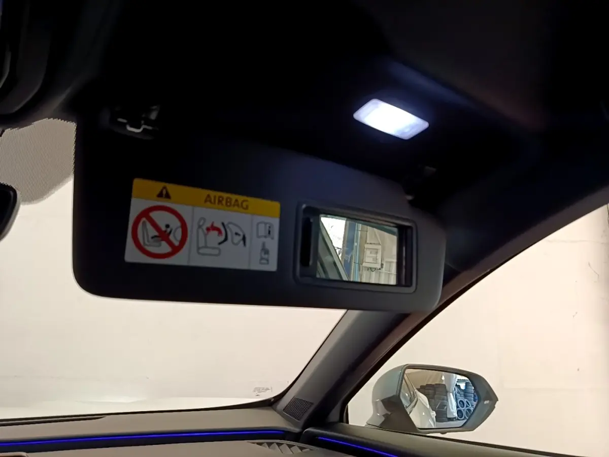 Intérieur du CUPRA Formentor 2023, vue côté passager avec pare-soleil ouvert et éclairage d'ambiance bleu visible.