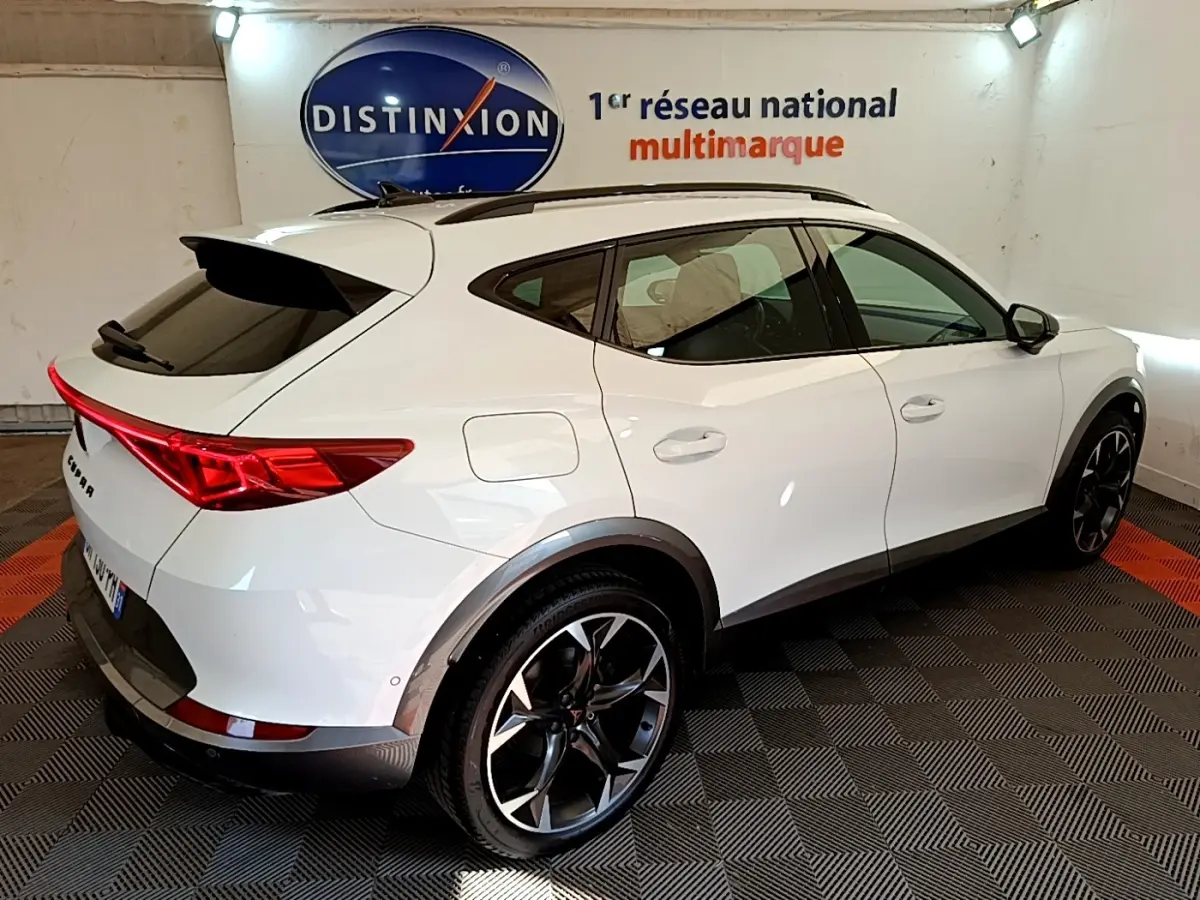 Vue 3/4 arrière droite d'un CUPRA Formentor blanc avec toit noir et jantes alliage noires en showroom.
