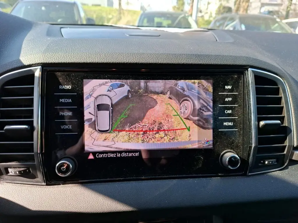 Vue intérieure de la porte avant gauche d’un Skoda Karoq gris, avec poignée et commandes de vitres.