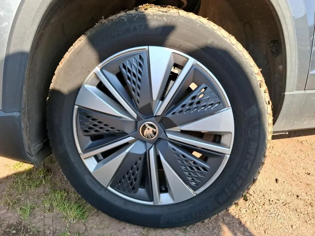 Vue 3/4 arrière droite d'un Skoda Karoq gris 2023 avec jantes alu 17 pouces et feux arrière LED dans un showroom.
