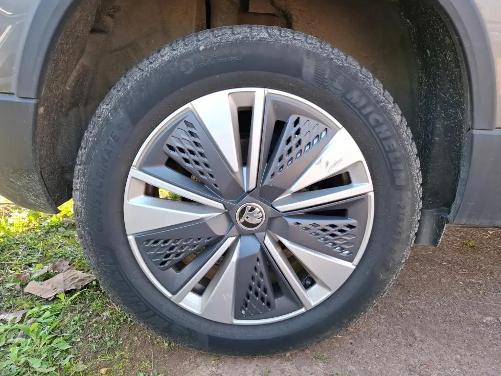 Vue 3/4 arrière droite d'un Skoda Karoq gris 2023 avec jantes alu 17'' et feux arrière LED dans un garage.