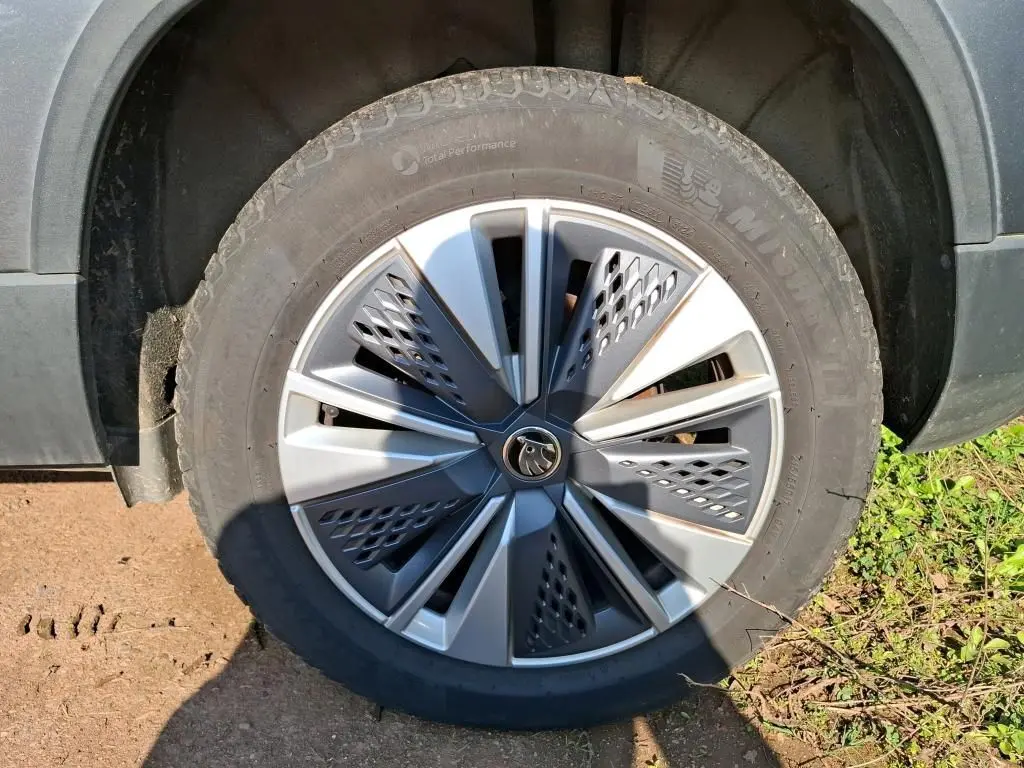 Vue de profil côté gauche d'un Skoda Karoq gris 2023 avec jantes alu 17 pouces dans un garage.
